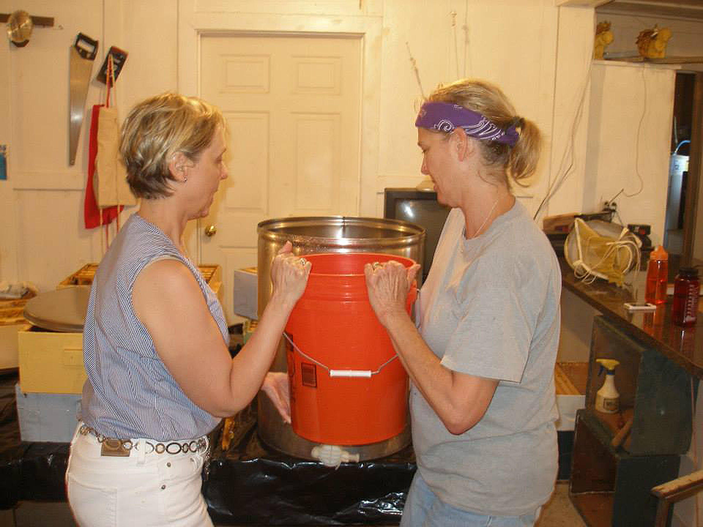 Transferring honey from the straining bucket into the holding tank.  This is where the honey will sit for about 48 hours to allow air bubbles to rise to the top in preparation for bottling.